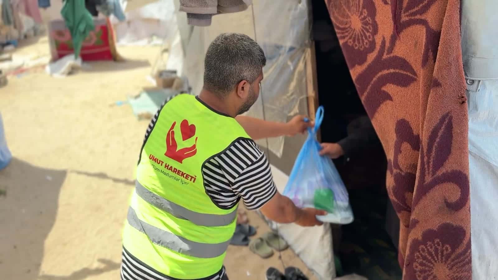 Gönüllü, çadır kampında yardım paketini teslim ederken